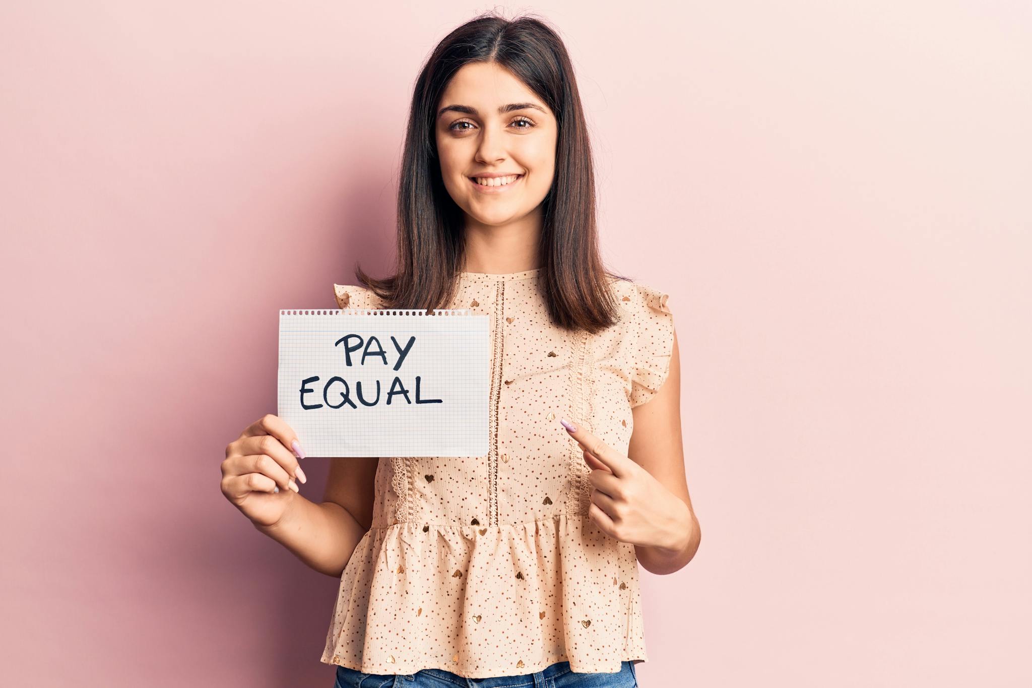Frau hält Schild nach mit der Aufschrift "Pay Equal" nach oben