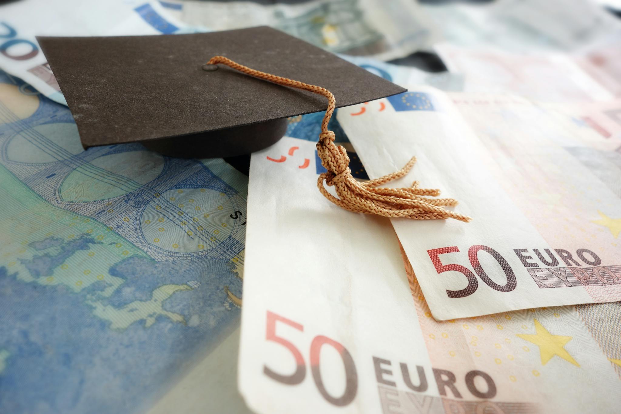 50 Euro Schein liegt auf Tisch mit Absolventenhut