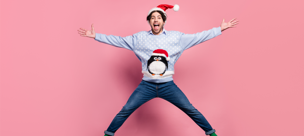 Mann in Weihnachtsoutfit springt glücklich in die Luft